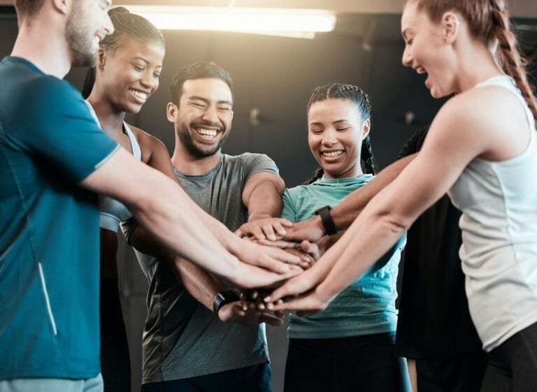 Shot of a group of friends with their hands stacked in motivation at the gym
